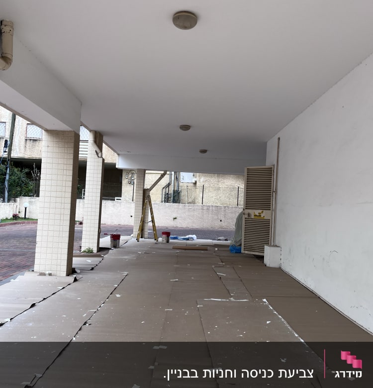 קרטונים על הרצפה, סולם, דליים, קיר לבן